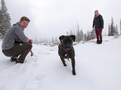 Dakota the dog outside in the snow with adopters