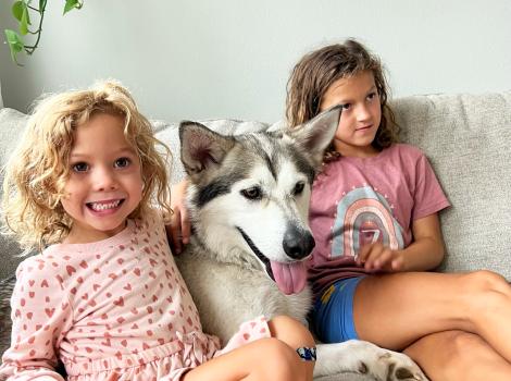Midas the dog on a couch with two kids