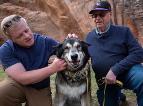 Shadow the dog with two people petting him