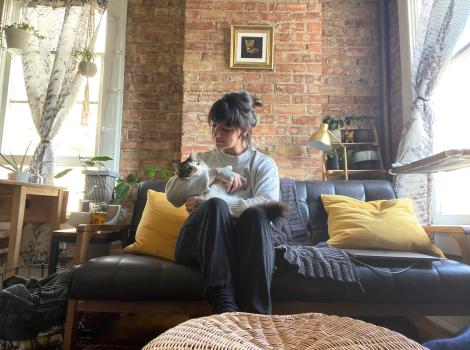 Paula holding Squeegee the cat while sitting on a couch