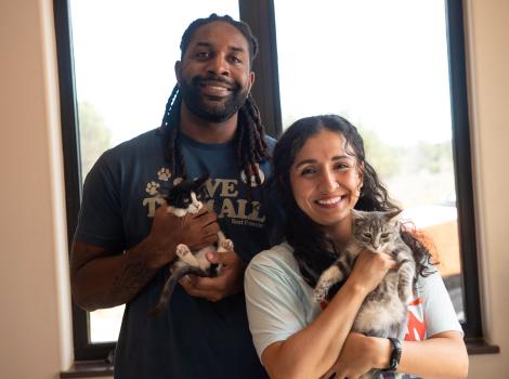 Abdul and Shamiyan holding kittens in front of a window