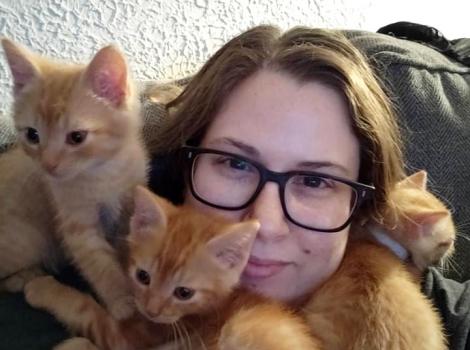 Jennifer Ronzello with three orange kittens surrounding her face