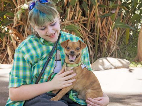 Athena holding a smiling Gremlin the dog in her lap