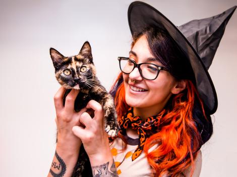Person dressed as a witch holding a tortoiseshell cat