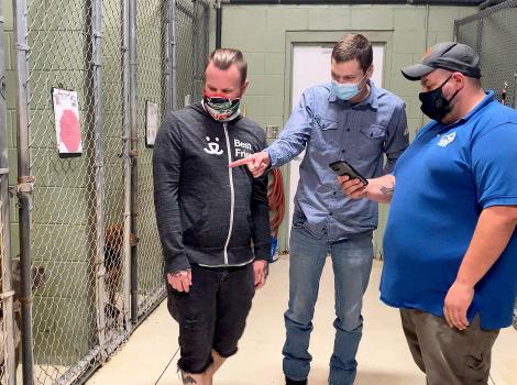 Three people from Horry County Animal Care Center and Best Friends in a dog kennel, with one person pointing