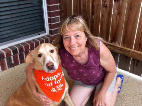 Fergus the dog with an adoption bandanna next to a smiling person