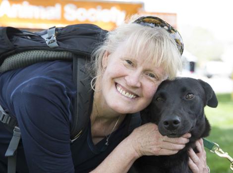 woman smiling with a black dog