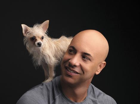 Dr. Kwane Stewart with a small dog on his shoulder
