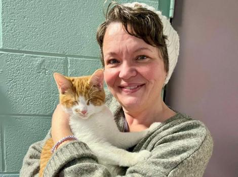 Lucky the cat being held by his adopter