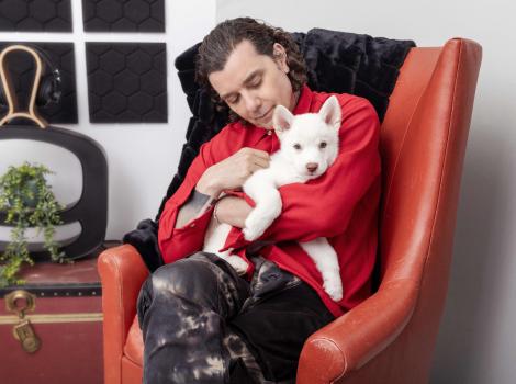Gavin Rossdale sitting in a chair holding a white puppy