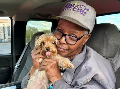 Person hugging a small dog in the driver's seat of a car