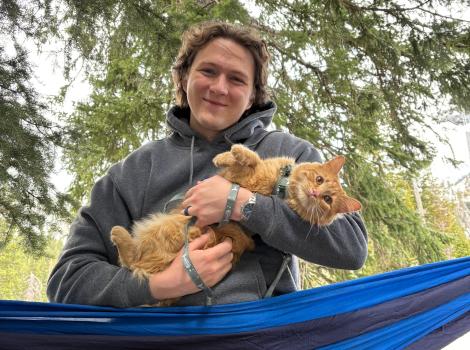 Ali holding an orange tabby cat while outside