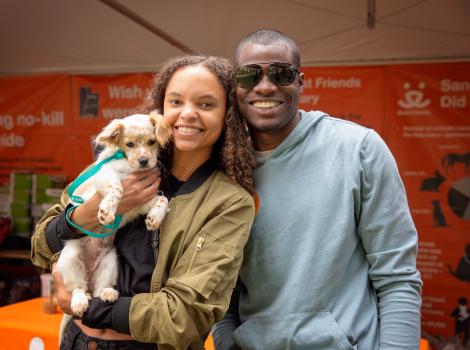 Smiling couple holding a puppy who they adopted at the NKLA Super Adoption