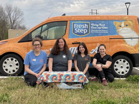 Four people in front of a Fresh Step branded van with a live trap covered with tie-die material