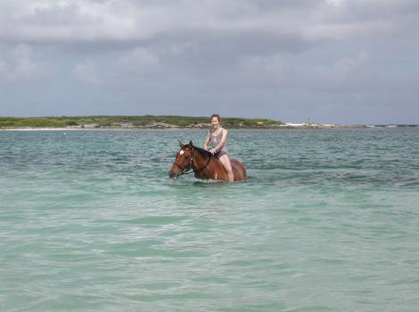 Volunteer Barbara riding a horse in the water