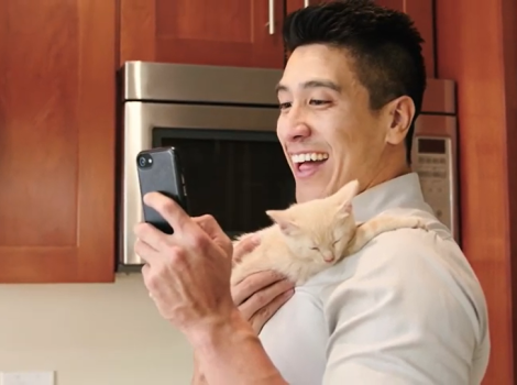 Smiling person taking a selfie with a kitten on his shoulder