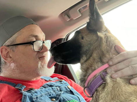 David Herrin and his service dog, Preciosa who is attempting to lick his face