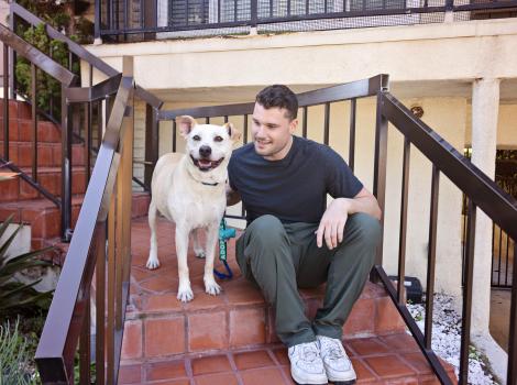 Dog and person sitting on outside steps at a housing complex