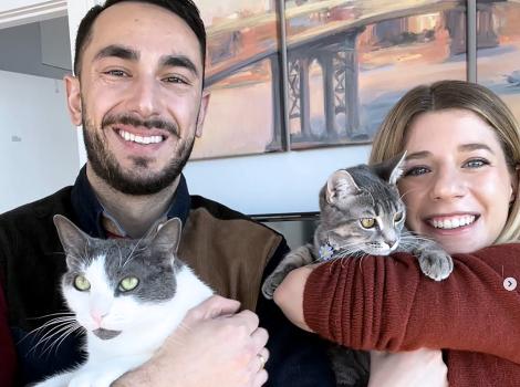 Cara and Matt smiling and holding Daisy and Gatsby their cats