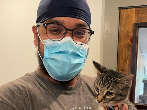 Volunteer Ramandeep Singh, smiling behind a mask, holding a tabby kitten