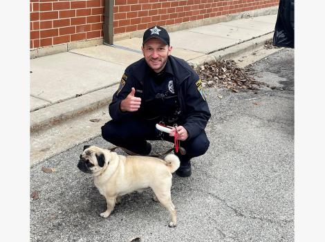 Community service officer Sean Bus giving a thumbs up sign with Wilson the pug