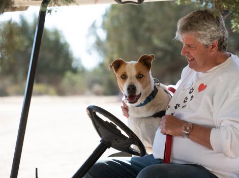 Caregiver Tim Dempsey in a golf cart with Abbott the dog