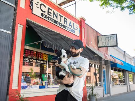 Calvin holding Sylvia the puppy in front of Central Book Exchange