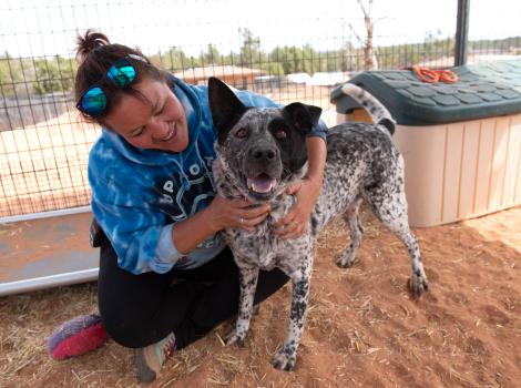Person smiling and hugging a black and white speckled dog