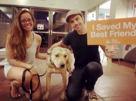 Erik Smith and a woman adopting Nash the dog, holding a 'I saved my best friend' sign