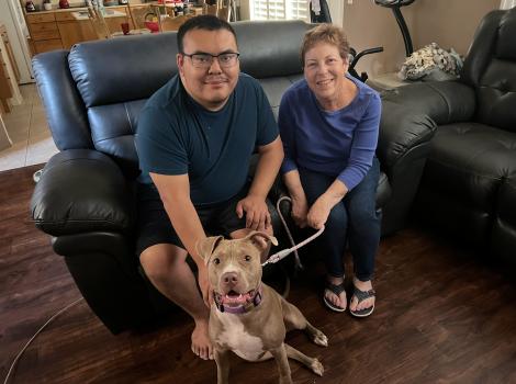 Ginny and Kenny Popvich with posing on a loveseat with a dog