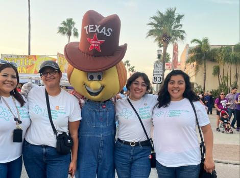 Ira and Vanni with two other people and a mascot wearing a cowboy hat with the word "Texas"