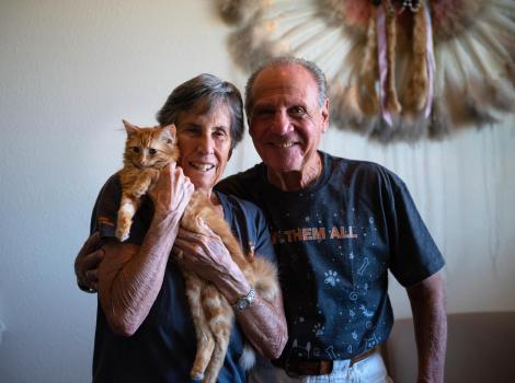 Brenda and Marty Winnick smiling and holding an orange tabby cat