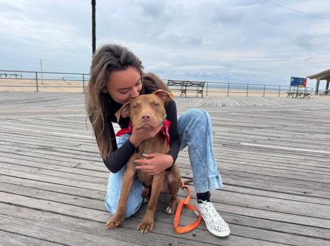 Masha kissing Cinnamon the dog on a boardwalk