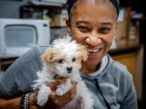 Tammie Sadler smiling and holding Bella the Maltese-mix puppy